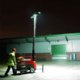 A man setting up a mini led lighting tower for use on a site.